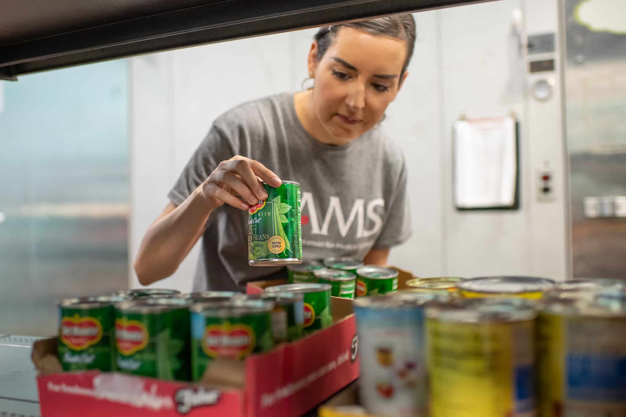 Volunteer working at UAMS school putting away canned goods